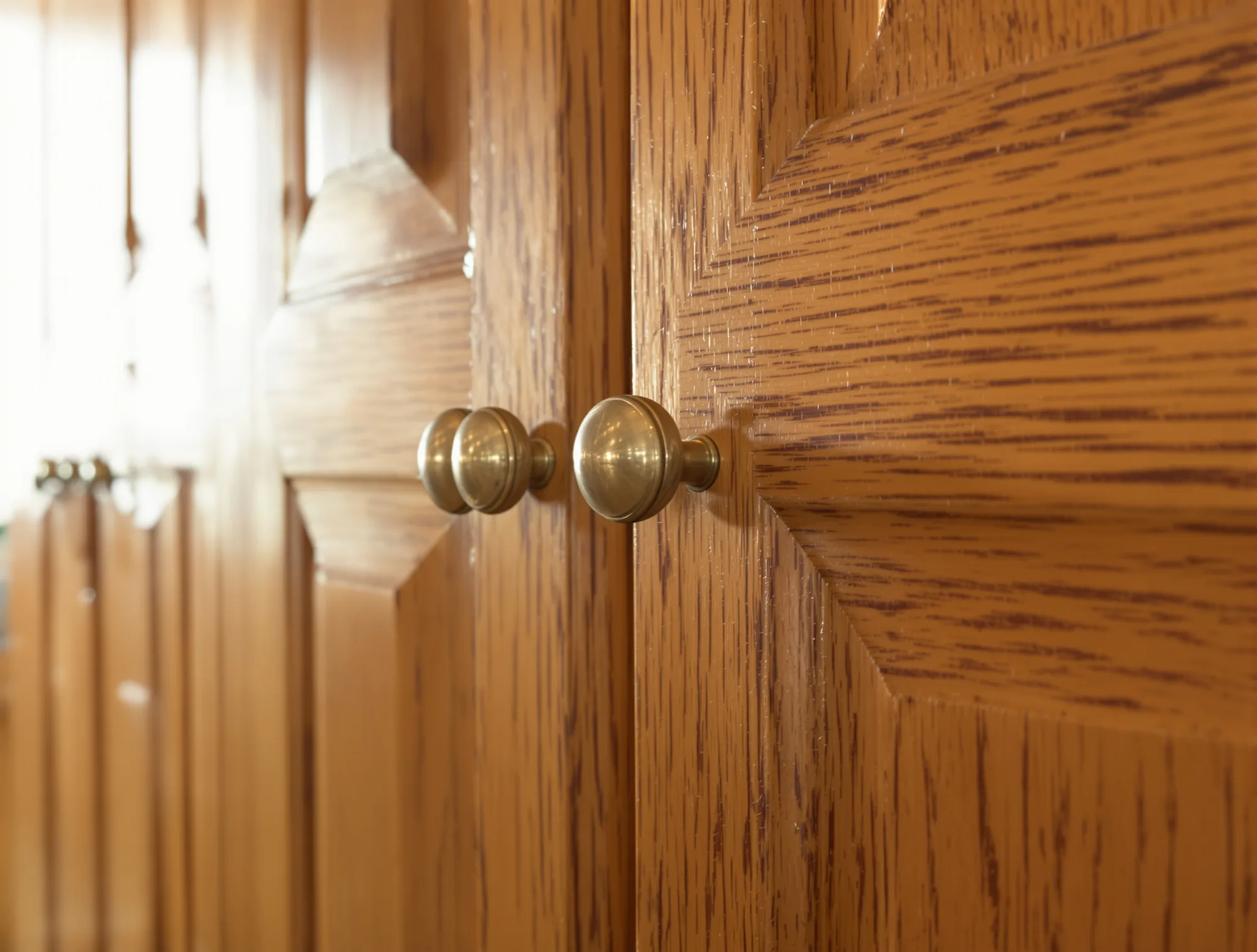 Dated honey oak kitchen cabinet doors with worn finish around the handles