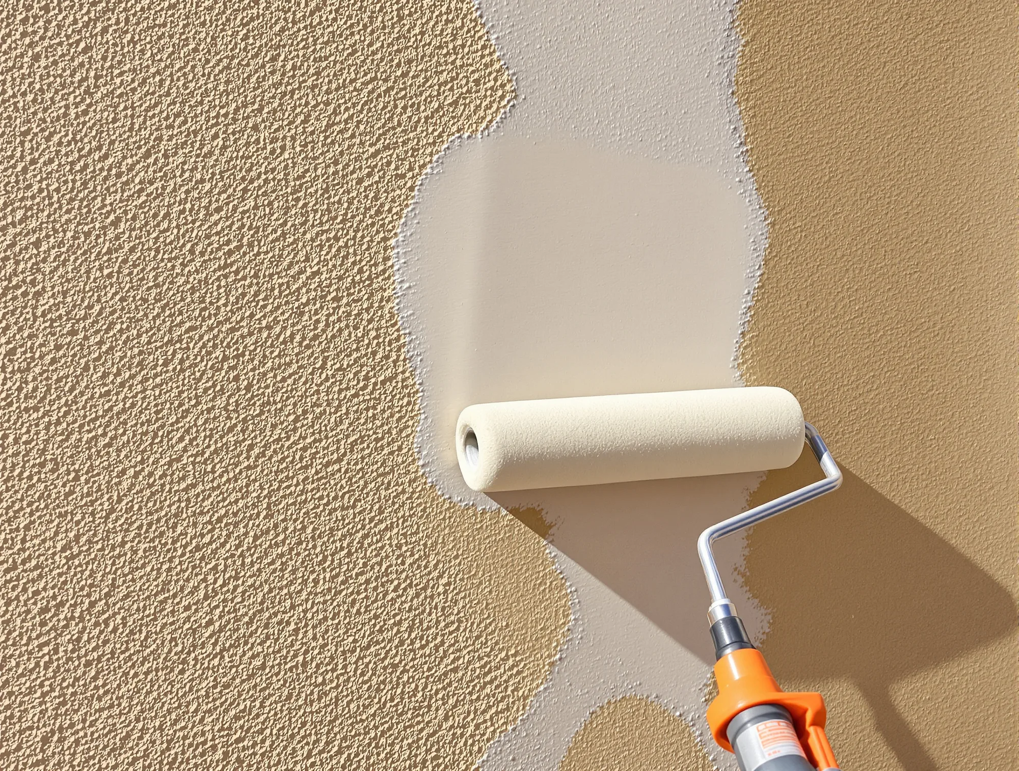 Roller spreading fresh paint over textured stucco
