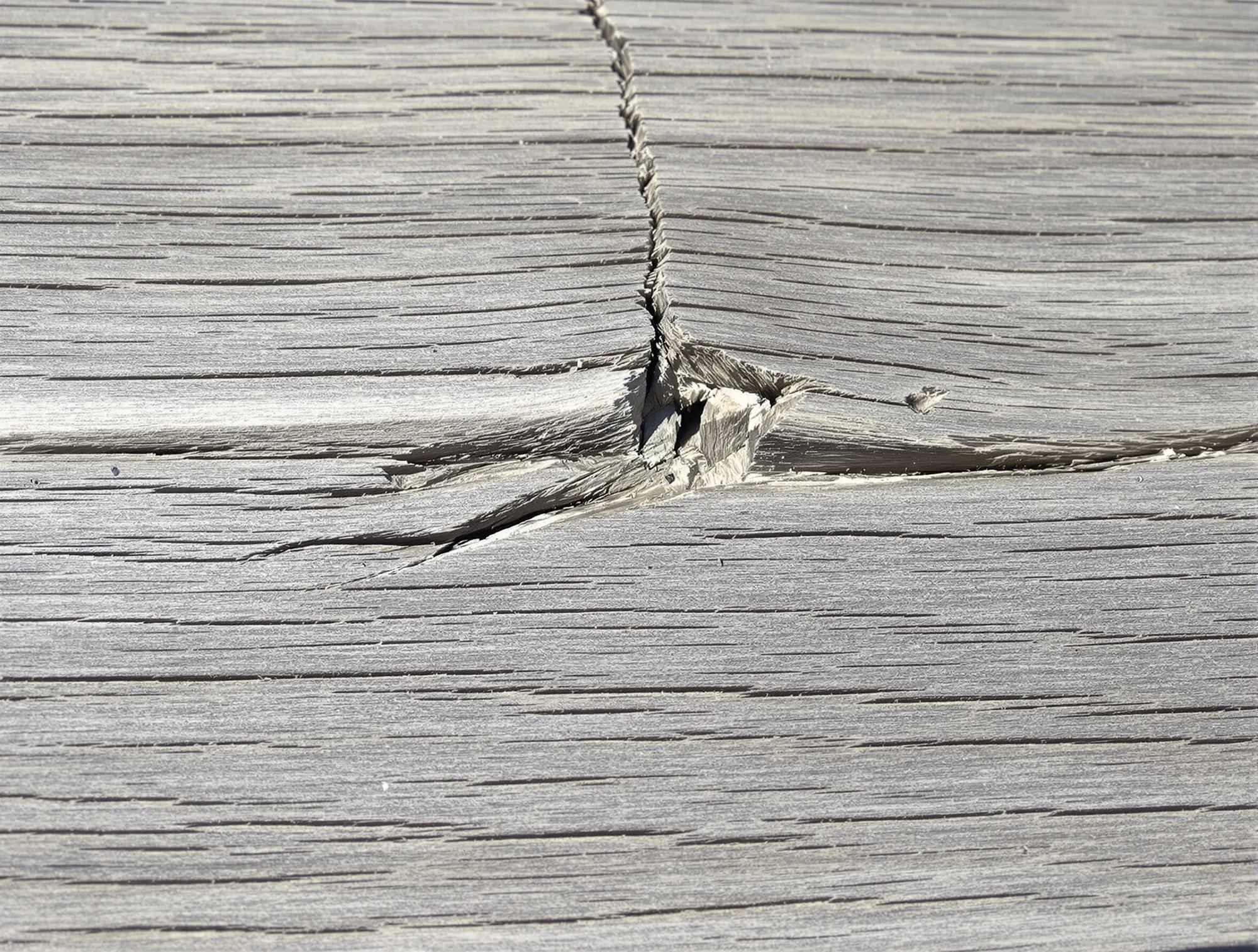 Macro view of a dry deck board with deep cracks running along the grain