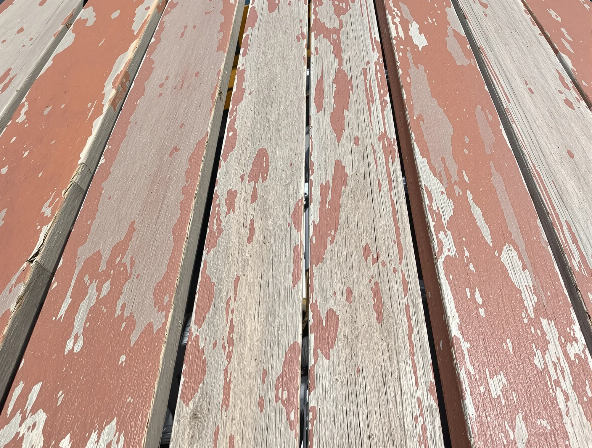 Old reddish deck stain peeling off weathered gray boards