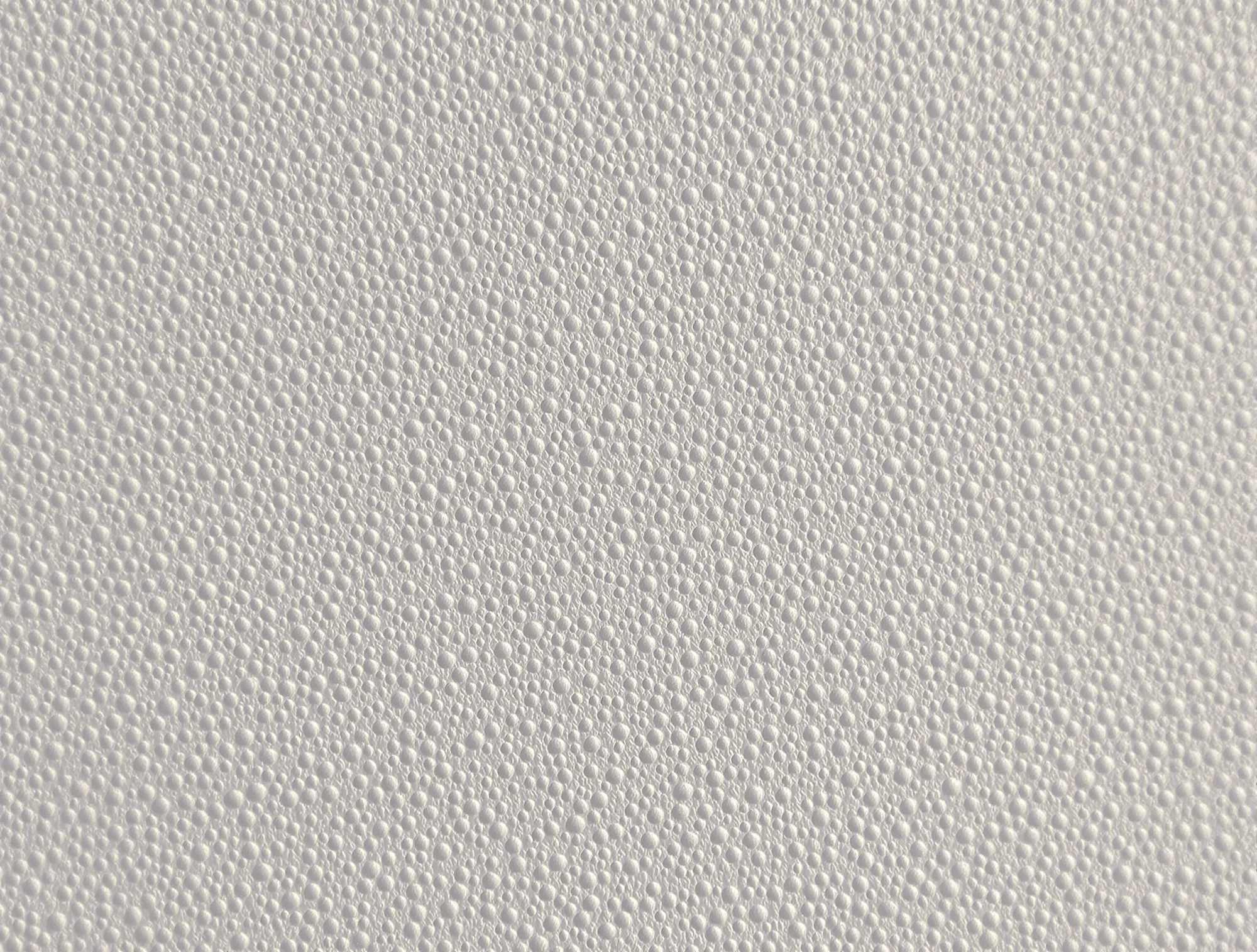 Close-up of fine orange peel texture on a warm white wall in side light