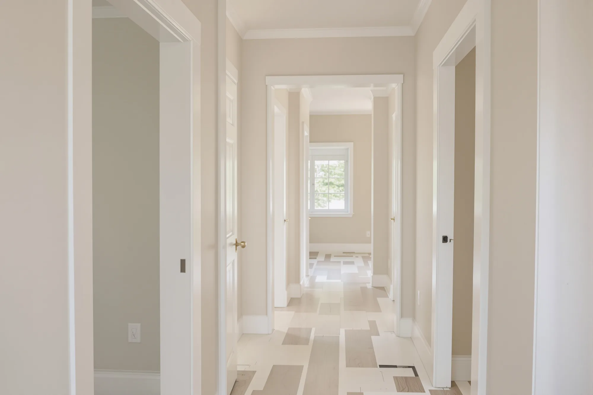 Hallway in a new home with bright white doors, casings and baseboards against pale greige walls