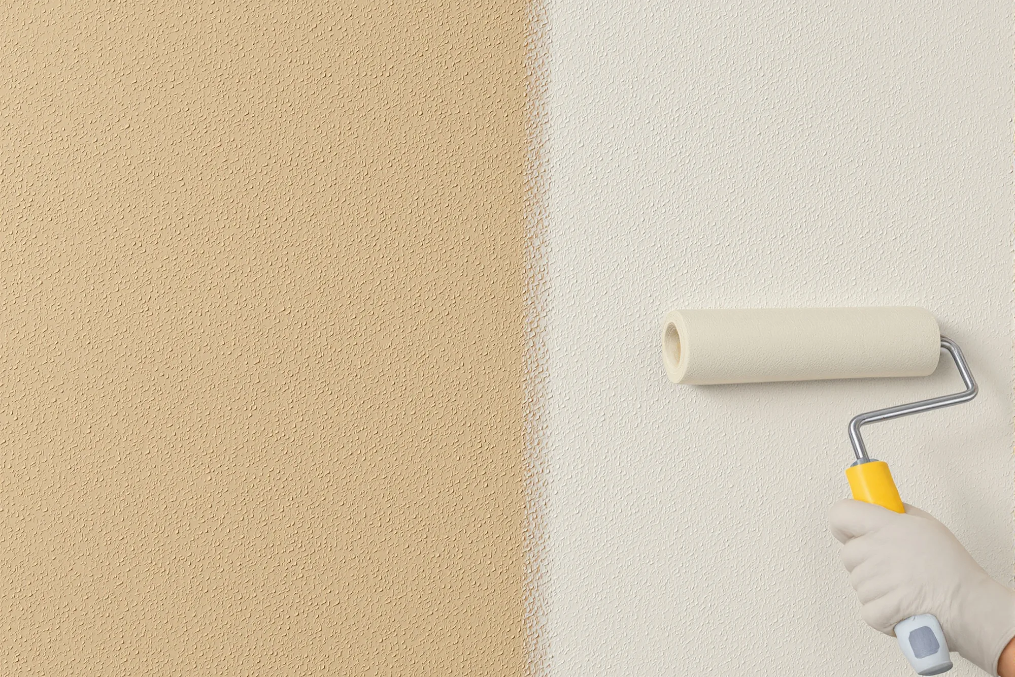 Fresh elastomeric coating rolled over textured stucco next to the old faded paint