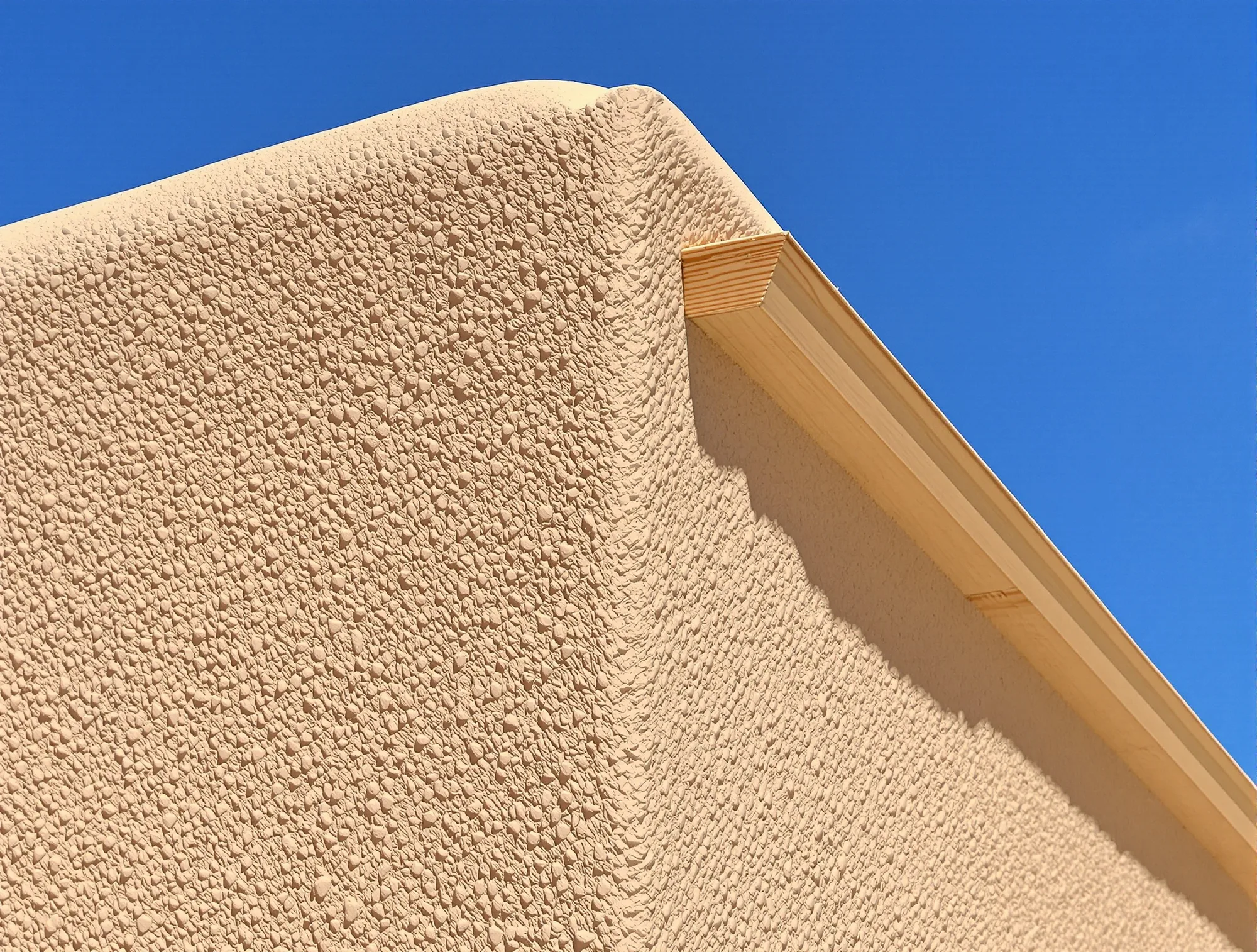 Integral color stucco finish coat in warm buff on a rounded adobe style corner